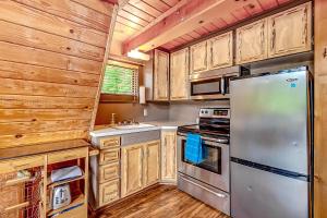 a kitchen with wooden cabinets and a stainless steel refrigerator at Kidd Island Bay Cabin Retreat in Coeur d'Alene