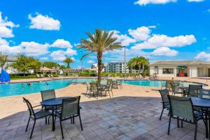 een zwembad met tafels en stoelen en een palmboom bij Endless Magic in Kissimmee