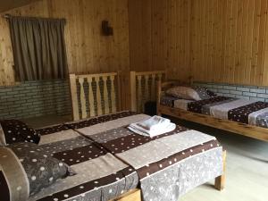 3 camas en una habitación con paredes de madera en Cottages in mountains en K'veda Bzubzu