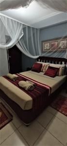 a bedroom with a large bed with red pillows at Tri M Waves Lodge in Ponta do Ouro