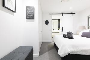 Un dormitorio con 2 camas y un banco. en The Port Melbourne Experience, en Melbourne