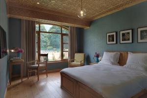a bedroom with a large bed and a window at Nadis - A handcrafted boutique hotel in Srinagar