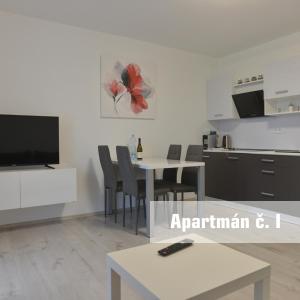 a living room with a kitchen and a table with chairs at Apartmány U koupaliště in Znojmo