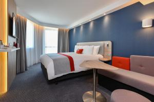 a hotel room with a bed, chair, and nightstand at Holiday Inn Express - Rouen Centre - Rive Gauche, an IHG Hotel in Rouen