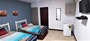 two twin beds in a room with a tv at Tri M Waves Lodge in Ponta do Ouro