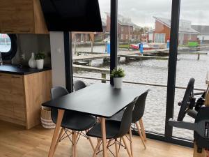Modern houseboat with roof terrace, on Uitgeestermeer في Uitgeest: طاولة وكراسي في مطبخ مطل على الماء