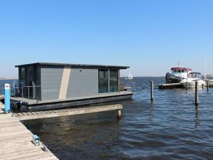 a small boat sitting on the water next to a dock at Modern houseboat with air conditioning located in marina in Uitgeest