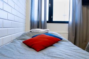 almohada roja sentada en una cama con ventana en Outdoor Hostel Laajis, en Jyväskylä