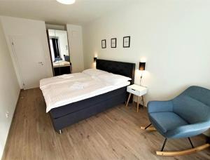 1 dormitorio con 1 cama y 1 silla azul en Lipno Port Apartment A103 en Lipno nad Vltavou
