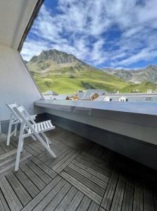 une chaise blanche sur un balcon avec vue sur la montagne dans l'établissement Plein centre station vue imprenable, à La Mongie