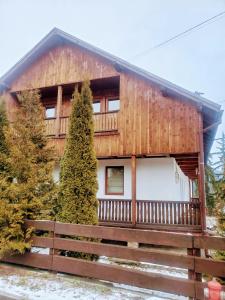 a log cabin with a fence in front of it at Papa la Șoni Gastro-Pensiune in Borsec