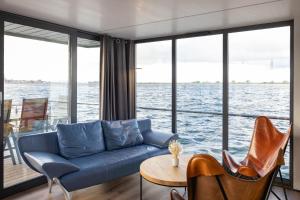 uma sala de estar com um sofá azul e cadeiras em exclusives Hausboot "Oma Ella" em Heiligenhafen