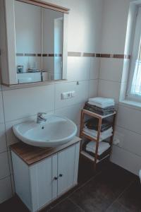 Baño blanco con lavabo y espejo en Ferienwohnung inmitten der Natur mit Sauna, en Steinau an der Straße