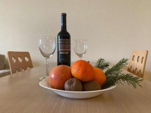 a bowl of fruit on a table with two wine glasses at Nevada Aparthotel in Pamporovo