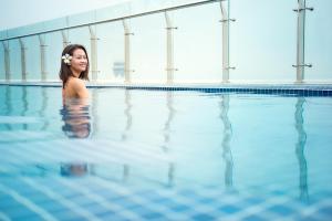 a woman standing in a swimming pool at Ibis Saigon Airport in Ho Chi Minh City