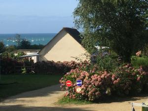 a yard with a bush of flowers and a house at Tente 3 chambres, petit camping familial vue mer in Plestin-les-Grèves