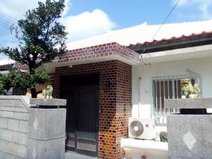 石垣島 一棟貸切りのお宿 ちゅら赤瓦 في جزيرة إيشيغاكي: مدخل من الطوب إلى منزل مع باب
