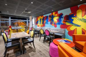 a restaurant with tables and chairs and a colorful wall at PopAlp in L'Alpe-d'Huez