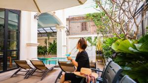 een vrouw aan een tafel op een patio met een drankje bij Mettavary Hotel in Phnom Penh