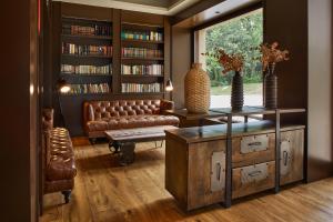 sala de estar con sofá de cuero y estante para libros en Mas Salagros EcoResort & SPA, en Vallromanes