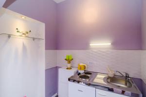 a small kitchen with a sink and purple walls at Apartment Tenega in Dubrovnik