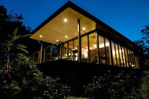 een huis met grote glazen ramen 's nachts bij Glass On Glasshouse in Glass House Mountains