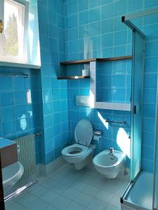 Baño azul con aseo y lavamanos en Delizioso monolocale, en Dobbiaco