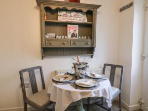 a dining room table with two chairs and a shelf with food at Little Daisy Cottage in Hornsea