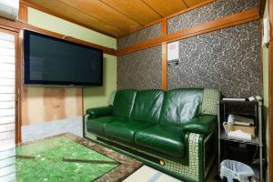 a green leather couch in a room with a flat screen tv at LJ Inn Fushimi Inari伏見稲荷 in Momoyama-chō