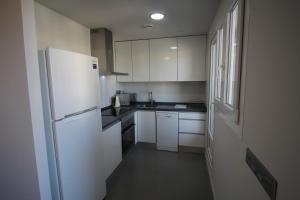 een keuken met witte kasten en een witte koelkast bij 0704 Ap Victoria I in Denia
