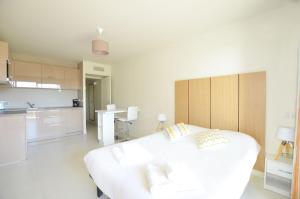 a white room with a white bed and a kitchen at La Perle d'Eze - Aparthotel in Éze