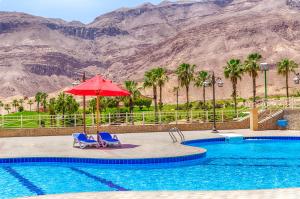 une piscine avec deux chaises et un parasol et des palmiers dans l'établissement Porto Sokhna Apartment powered By Amer-Group Family Only, à Ain Sokhna