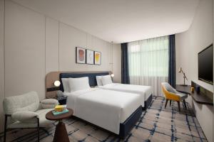 Cette chambre comprend un lit blanc et une télévision. dans l'établissement voco Wuhan Xinhua, an IHG Hotel, à Wuhan