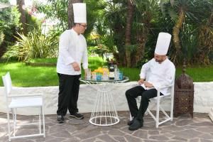 zwei Männer, die Köche tragen, Hüte neben einem Tisch stehen in der Unterkunft Hotel Majestic in Lido di Jesolo