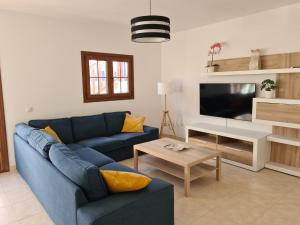 Una sala de estar con un sofá azul y un televisor en Luxury 4-Bedroom Villa With Heated Pool + Sea View, en Playa Blanca