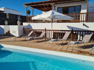 una casa con piscina con sedie e ombrellone di Luxury 4-Bedroom Villa With Heated Pool + Sea View a Playa Blanca