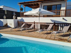 una casa con piscina con sillas y sombrilla en Luxury 4-Bedroom Villa With Heated Pool + Sea View, en Playa Blanca