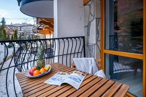a table with a bowl of fruit and a newspaper on a balcony at Apart4You Apartamenty Bory Sweet Time in Zakopane