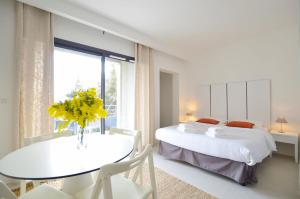 a bedroom with two beds and a table with yellow flowers at La Perle d'Eze - Aparthotel in Éze