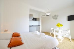 a white bedroom with a bed and a table at La Perle d'Eze - Aparthotel in Éze