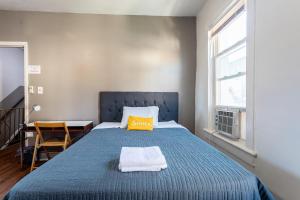 Un dormitorio con una cama azul con una almohada amarilla. en Best Home To Visit NYC-Subway Access en Newark
