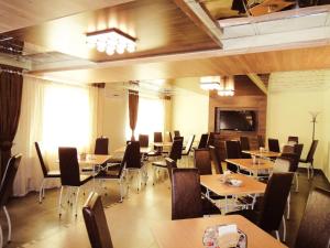 Uralochka Hotel في تشيليابنسك: مطعم بطاولات وكراسي وتلفزيون بشاشة مسطحة