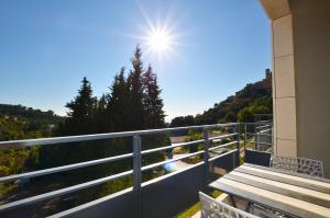 a balcony with a wooden table and the sun in the sky at La Perle d'Eze - Aparthotel in Éze
