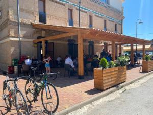 塞埃欣的住宿－Albergue La Estación，两辆自行车停在餐厅外面,有人坐在桌子旁