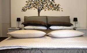 a bed with three pillows and a tree on the wall at B&B Al Viale in Macerata