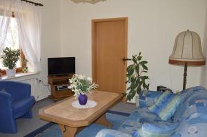 Una sala de estar con un sofá azul y una mesa. en Timmerloher Weg, Ferienwohnung, en Schneverdingen