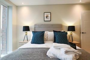 a bedroom with a large bed with blue pillows at Portfolio Apartments - Welwyn Town Centre in Welwyn Garden City