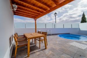 a patio with a table and chairs and a swimming pool at Luxury Villas Anjomacar in Teguise