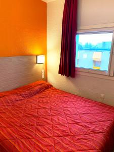 una camera da letto con un grande letto rosso e una finestra di Premiere Classe Thionville - Yutz a Basse-Yutz
