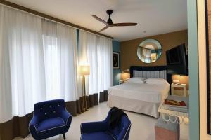 a bedroom with a bed and two chairs and a mirror at Hotel Majestic in Lido di Jesolo